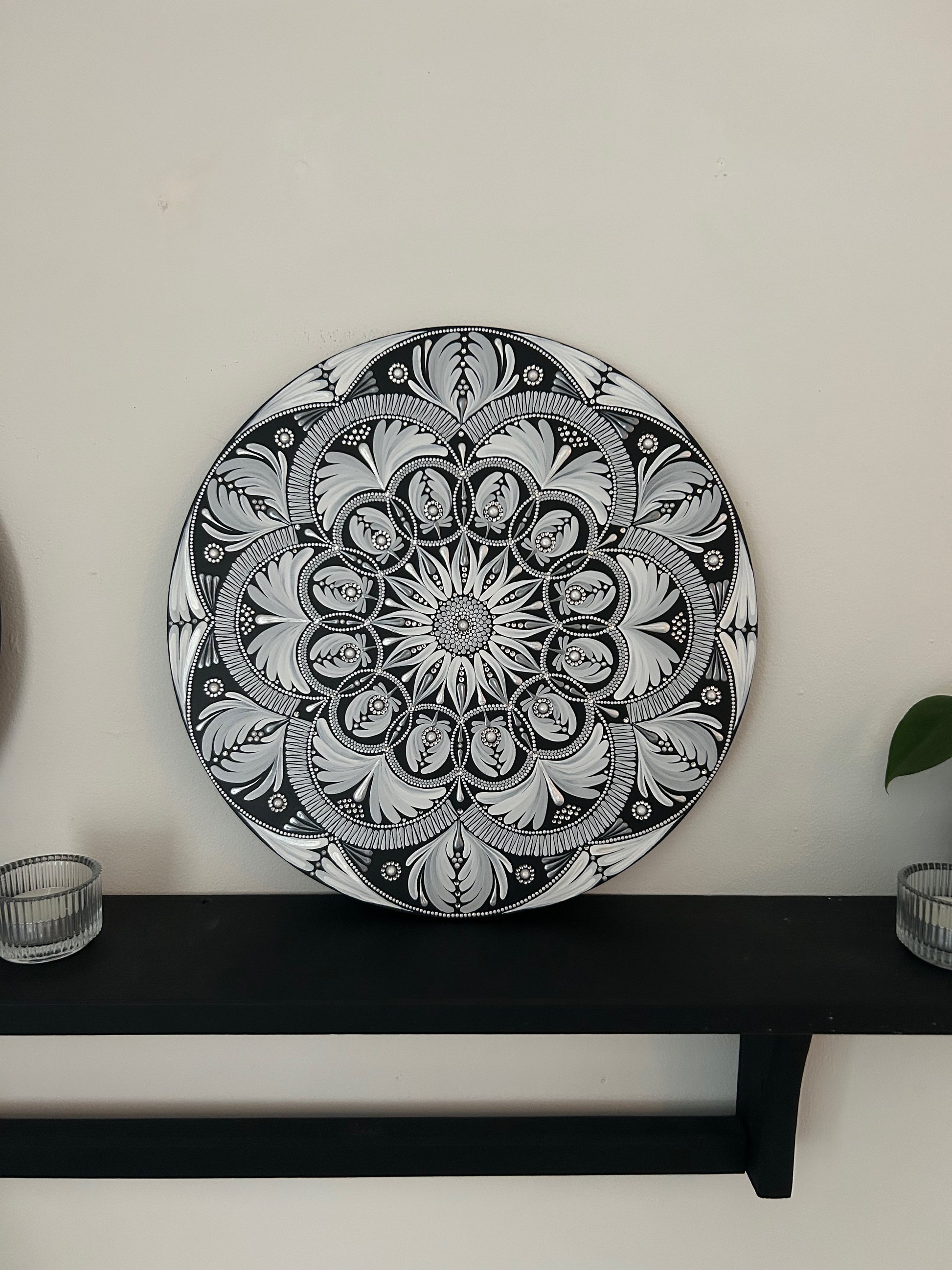 Decorative black and white mandala plate on a shelf against a white wall